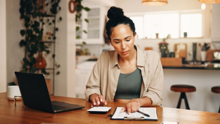 Woman, calculator and laptop in apartment with document, administration and budget for utility bills. Person, calculation and computer in home with paperwork, financial planning or household expense.