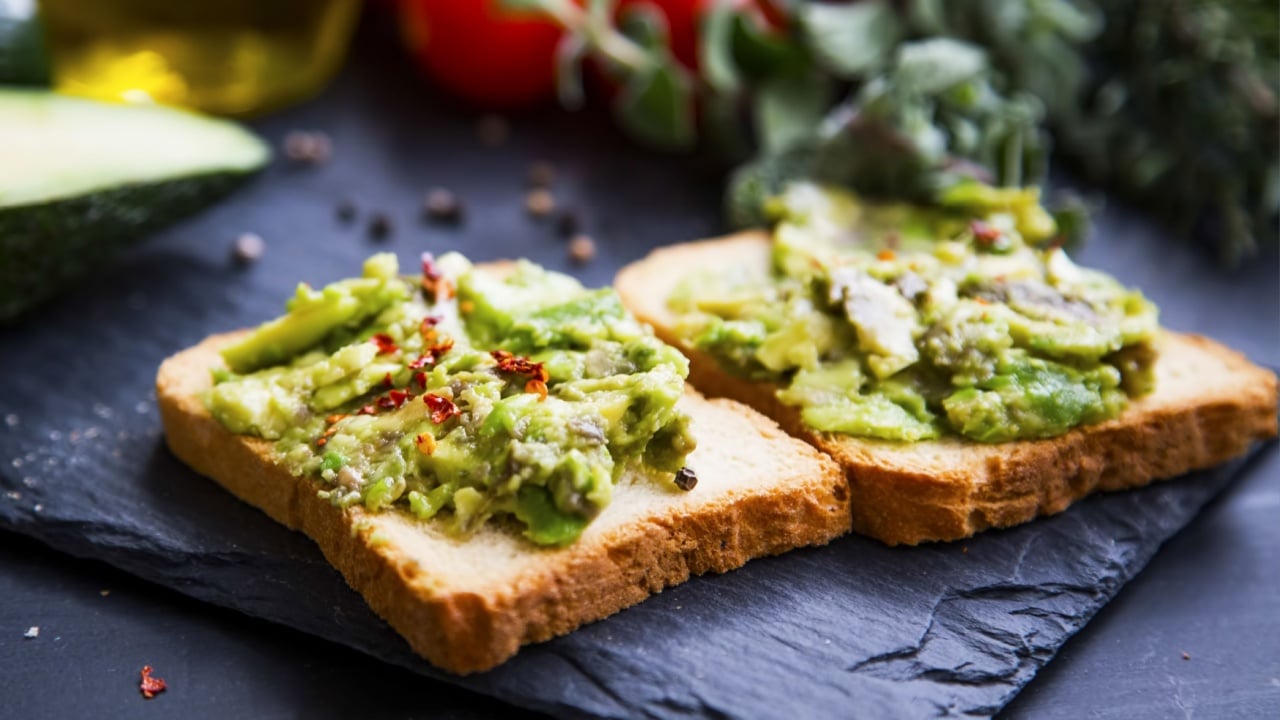Smashed avocado on toast, tasty healthy appetizers with cherry tomatoes and herbs, olive oil