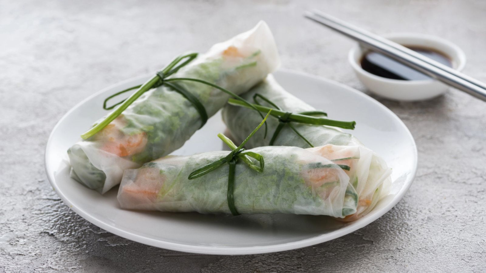 Tasty and served spring rolls with on white plate with soy sauce