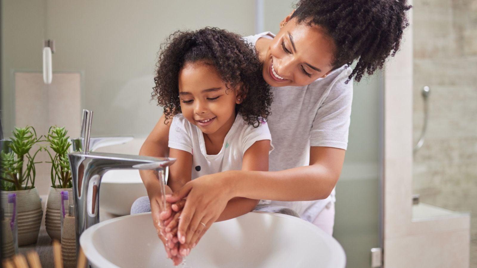 washing hands and child with mom rinsing, cleaning and good hygiene against bacteria or germs for infection or virus protection in bathroom