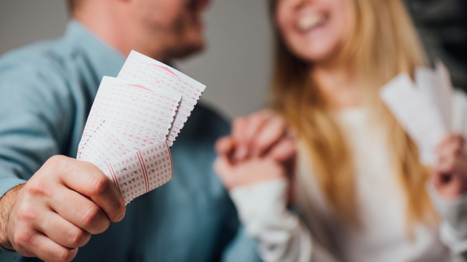 Cropped view of happy man and woman holding hands while holding lottery tickets
