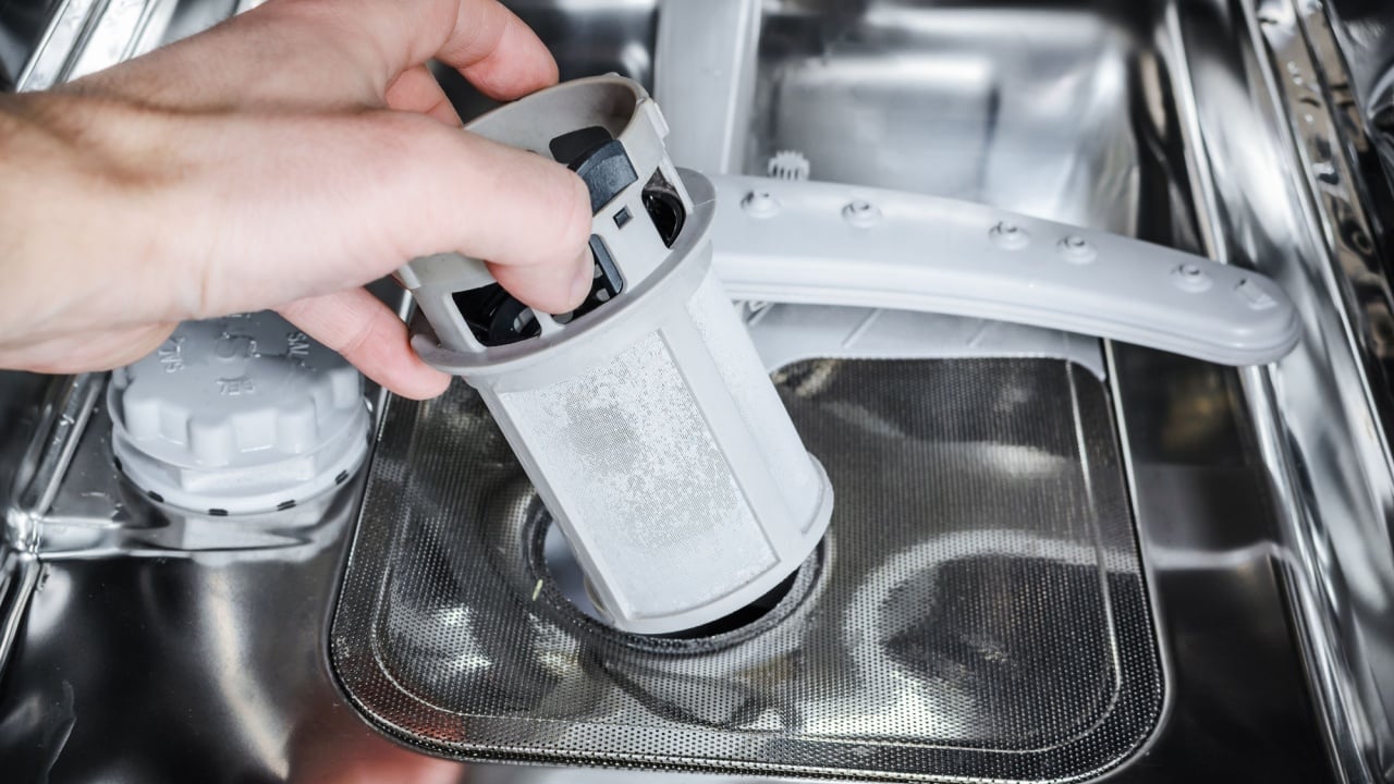 Maintenance of home appliances. Man cleans the filter in the dishwasher.