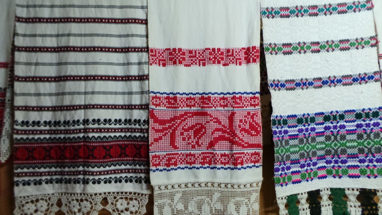 Close up beautiful intricate patterns on white scarves hung up against a wooden wall