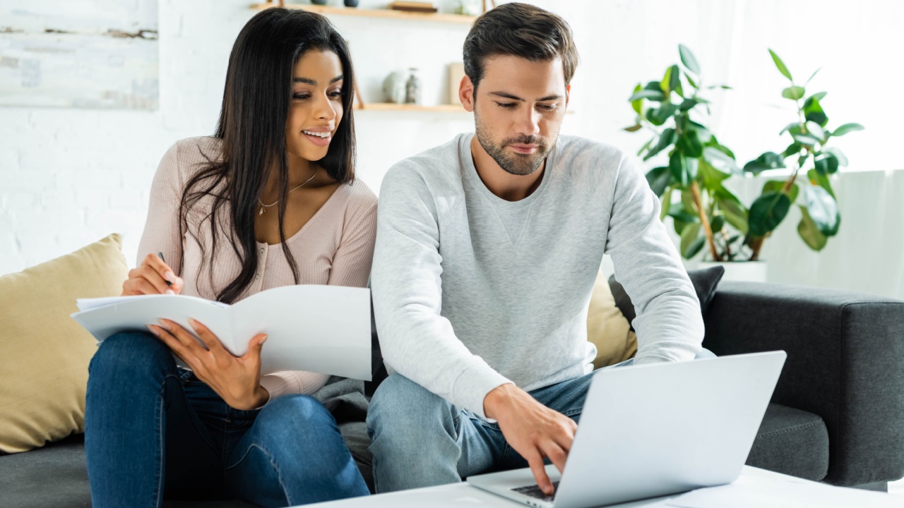 african american woman doing paperwork and handsome man using laptop in apartment