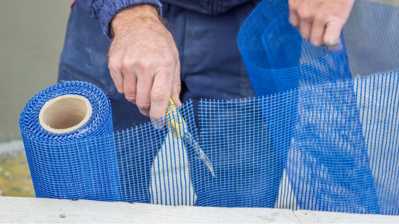 building worker sets plastic grid with cutter for plaster worker