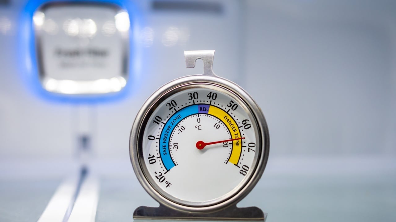 Refrigerator thermometer in empty cold storage unit. Refrigeration safety gauge displaying unsafe food temperature warning.