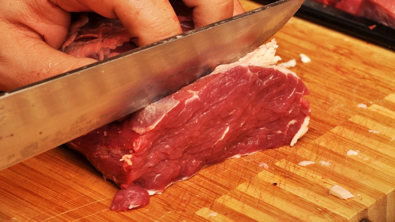 Clean very fresh red raw meat and a sharp knife, on cutting board