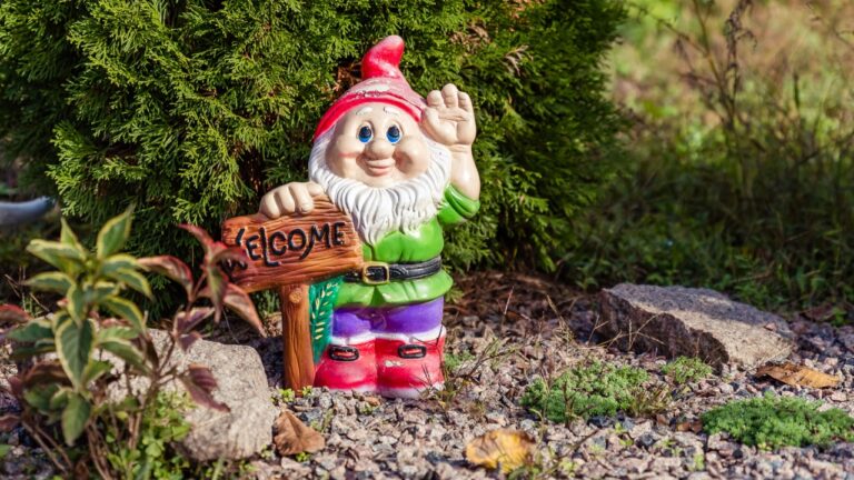 Figurine of a garden gnome in the garden with a sign.