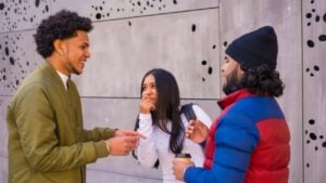 Urban style, three black Latino friends having fun in the street and talking to each other. Afro hair boy, brunette boy with long hair with hat