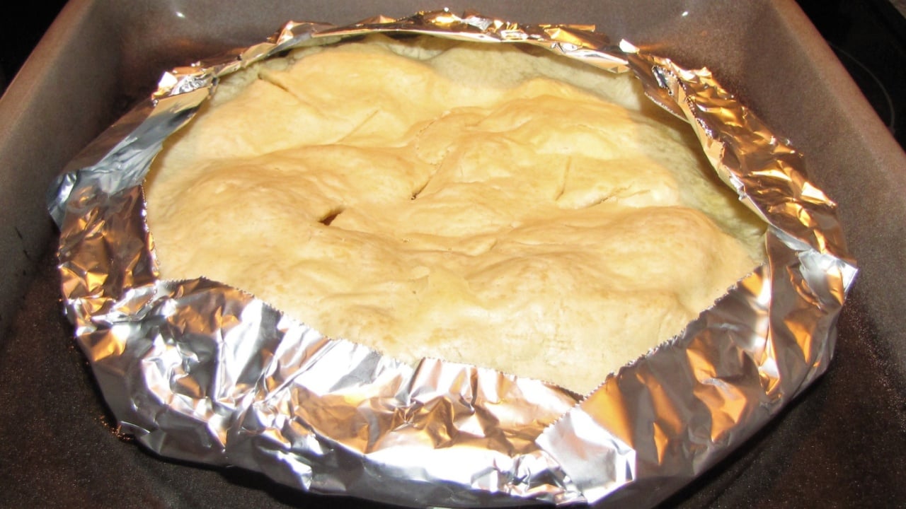 Home baked pie with tin foil wrapped edges to prevent burning