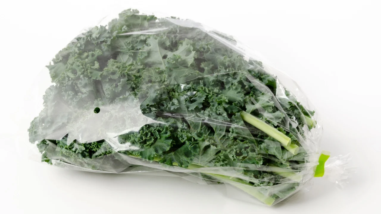 Fresh Curly green kale in plastic bag on white background