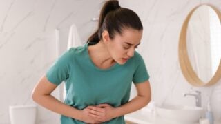 Young woman suffering from stomach ache in bathroom. Food poisoning
