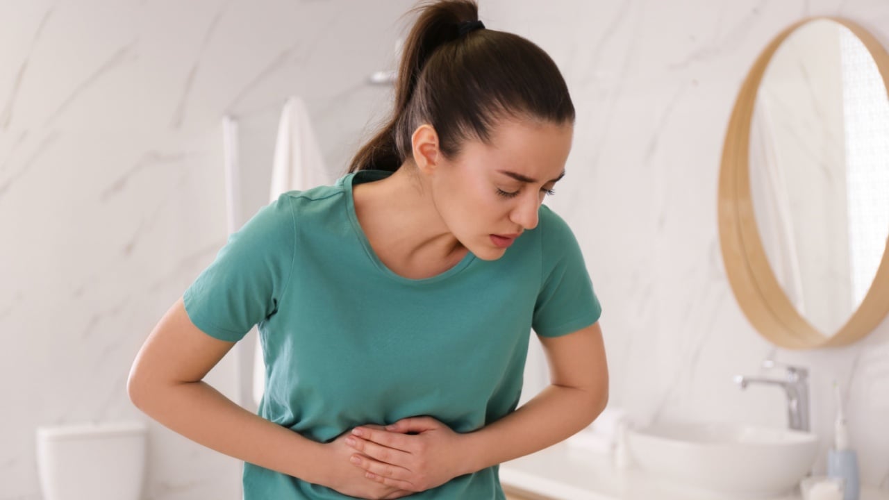 Young woman suffering from stomach ache in bathroom. Food poisoning