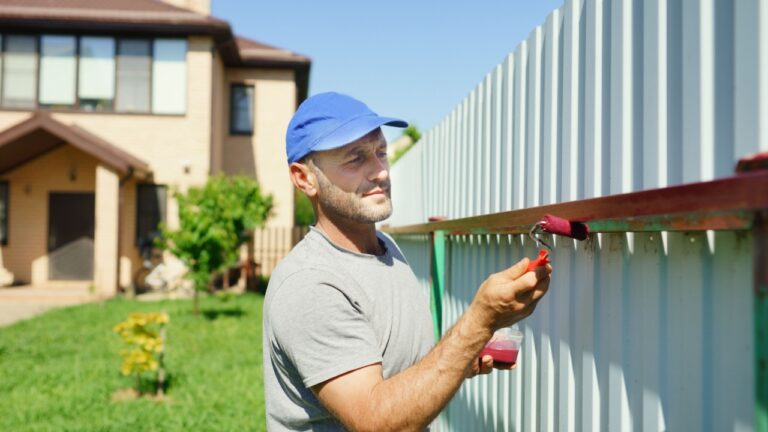 man painting a fence outdoor. repairs background. summer time activity.
