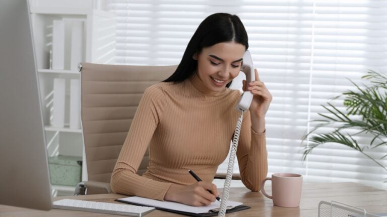 Secretary talking on phone at wooden table in office