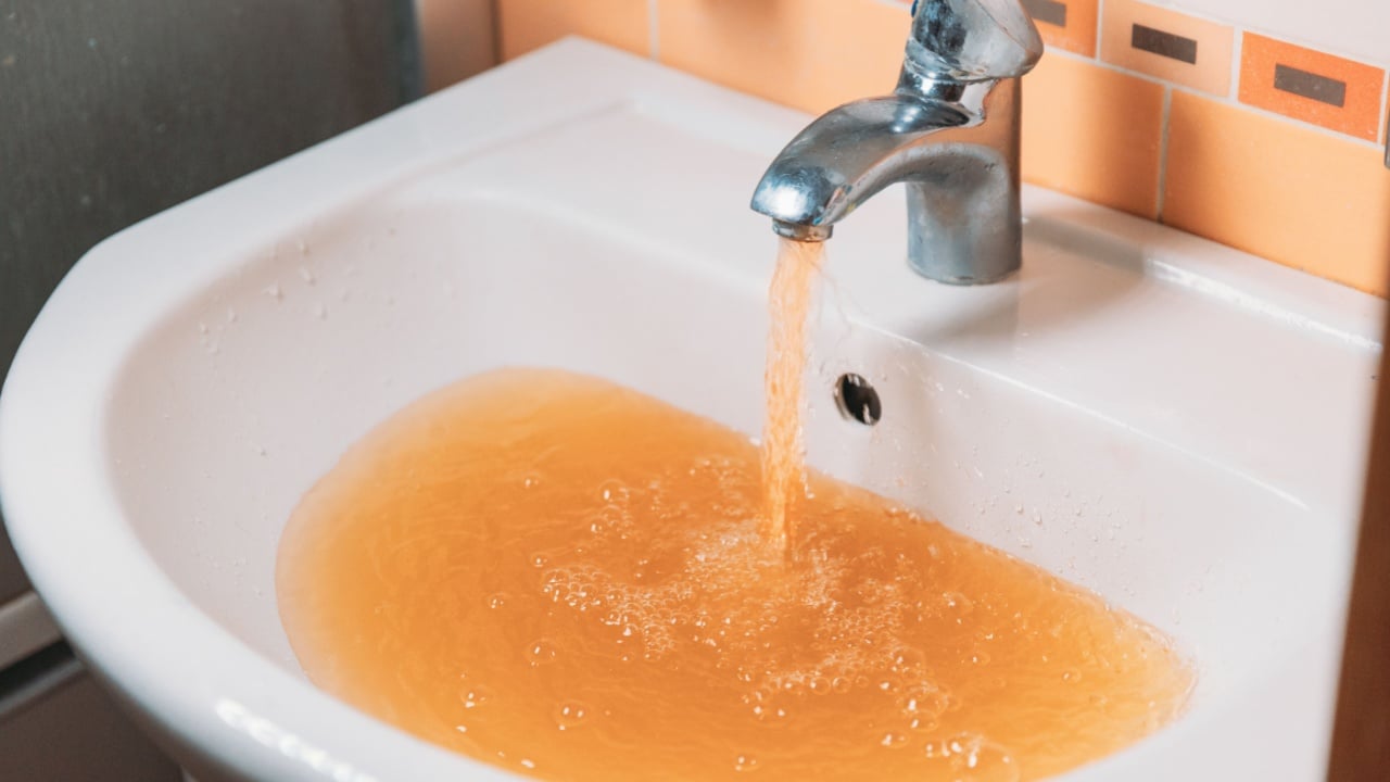 Rusty Water Pours From Tap. Water Pollution. Global Environment.