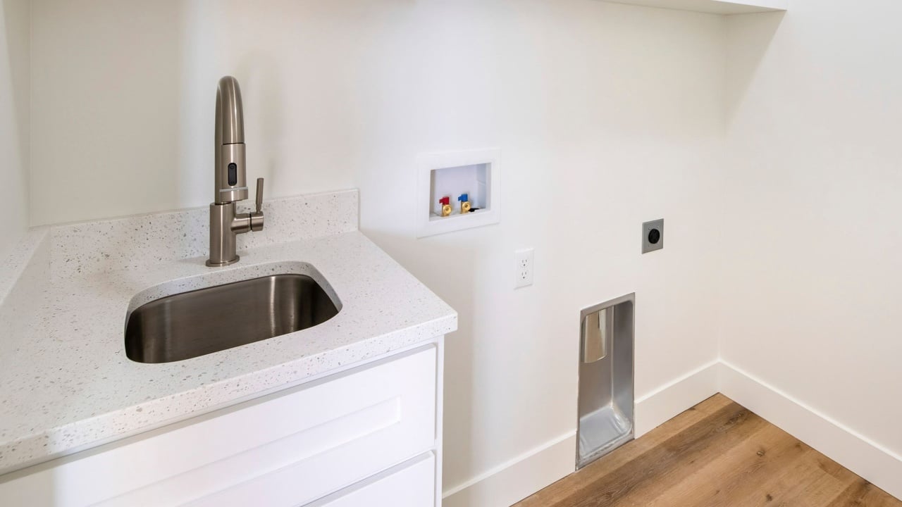 Square frame Empty white laundry room with top storage, laundry connections and dryer vent on the wall