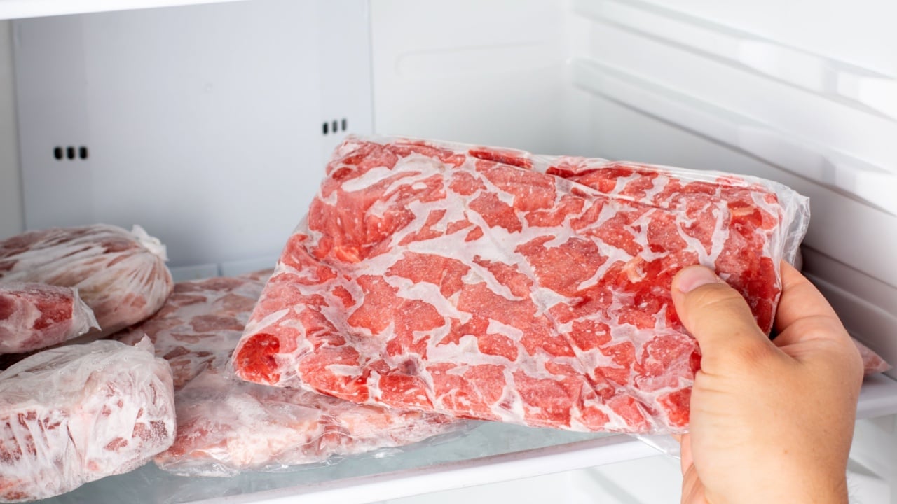 Closeup of hand choosing fresh raw meat in the freezer. Frozen food