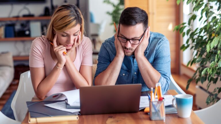 Couple checking their bills,using laptop while working at home in the living room.