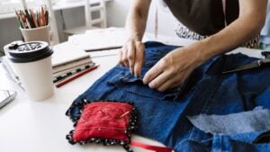 Mending Clothes, how to mend old Clothes. Sustainable fashion, Denim Upcycling Ideas, Using Old Jeans, Repurposing, Reusing Old Jeans, Upcycle Stuff. Woman seamstress cut and repair old blue jeans