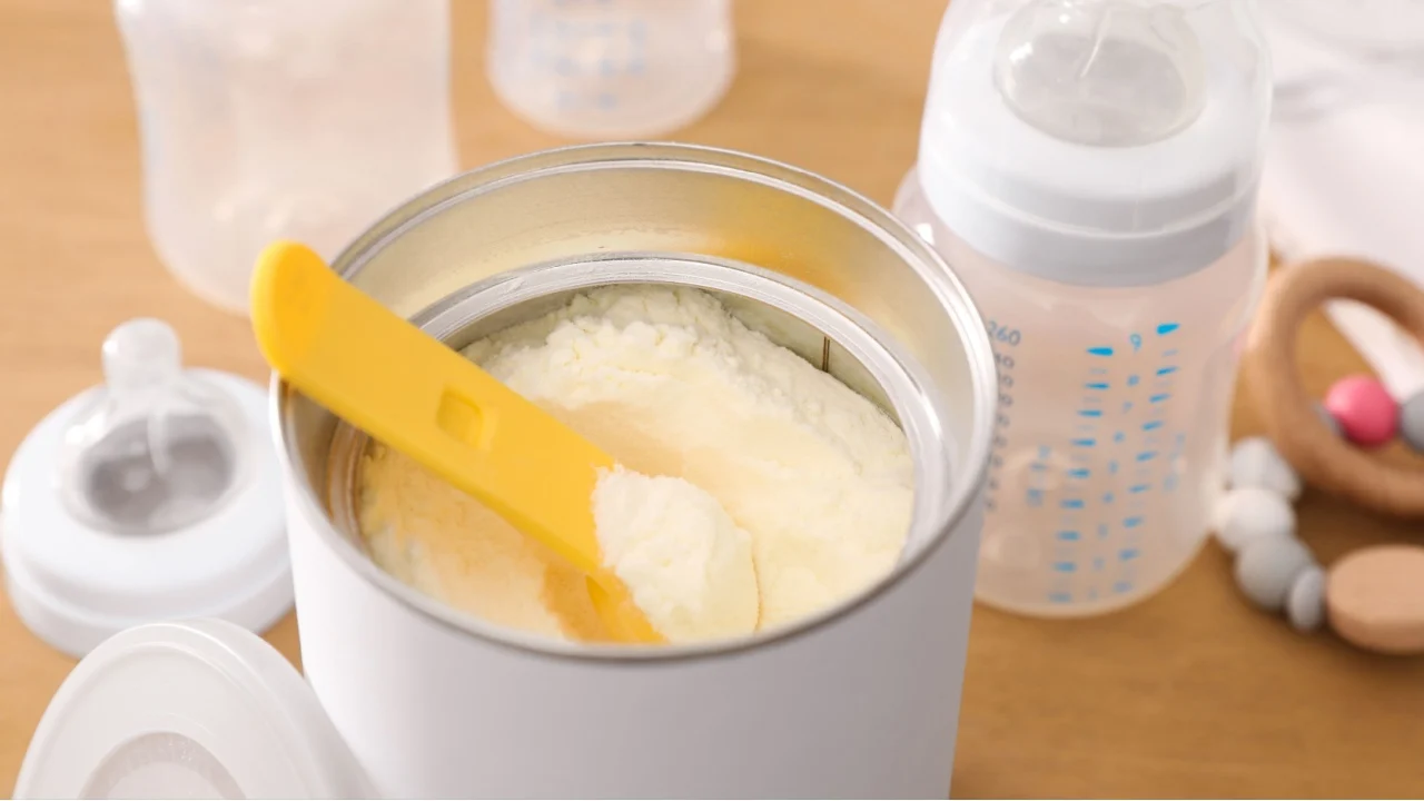 Can of powdered infant formula with scoop on table, closeup. Baby milk
