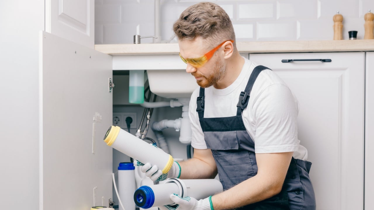 Plumber working replaceable dirty used aqua filter for filtration of reverse osmosis water.