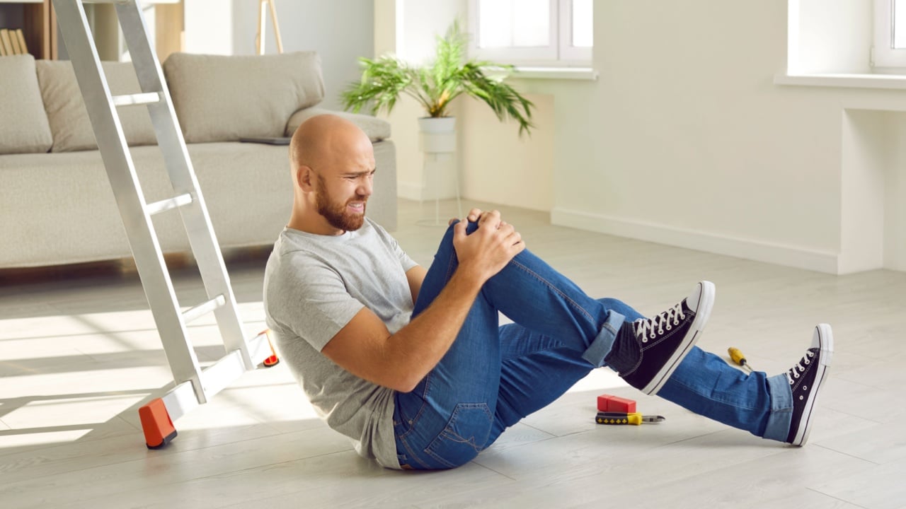Young person trips over an electric cord at home. Close up of a man who's wearing uncomfortable trainers stumbling on a power cable. Close up shot of his feet on the floor. Domestic accident concept