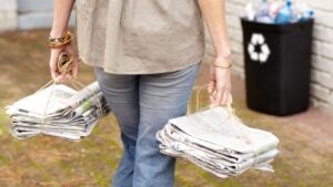 Doing her part to help the environment. Cropped view of a woman preparing to recycle two stacks of old newspapers.