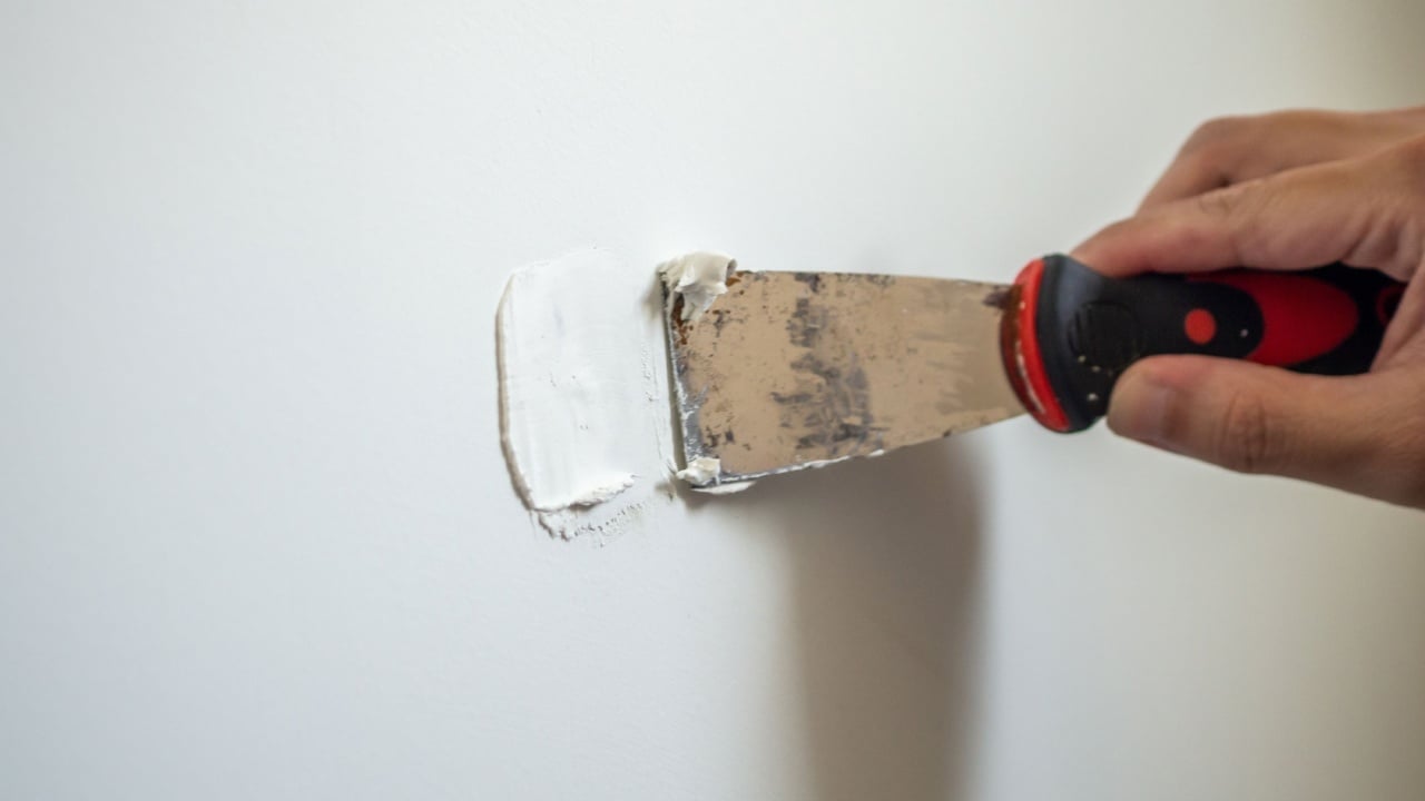 Man repairing crack white wall with spatula