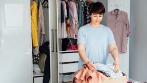 Woman selecting clothes from her wardrobe for donating to a Charity shop. Decluttering, Sorting clothes and Cleaning Up. Reuse, second-hand