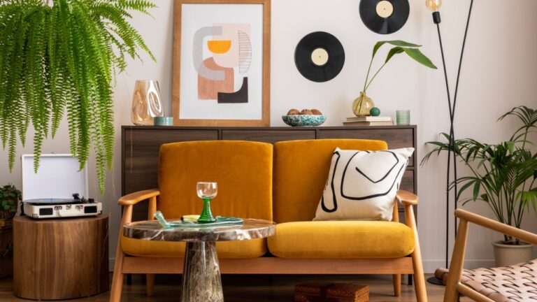 Vintage retro composition of living room interior with mock up poster frame, yellow velur sofa, plants, wooden commode, coffee table and personal accessories. Stylish home decor.