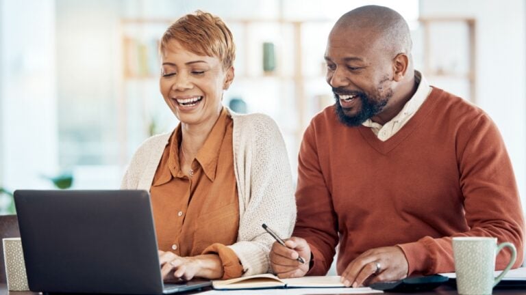 Smile, black couple and laptop doing budget, check savings amount and investments together for retirement plan. Retired, mature man and senior woman confirm finances, being happy and laugh at home.