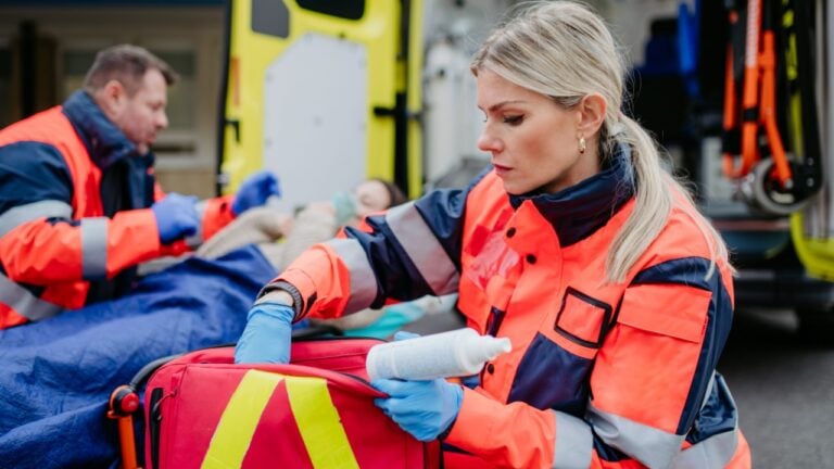 Rescuers taking care of patient, preparing her for transport.