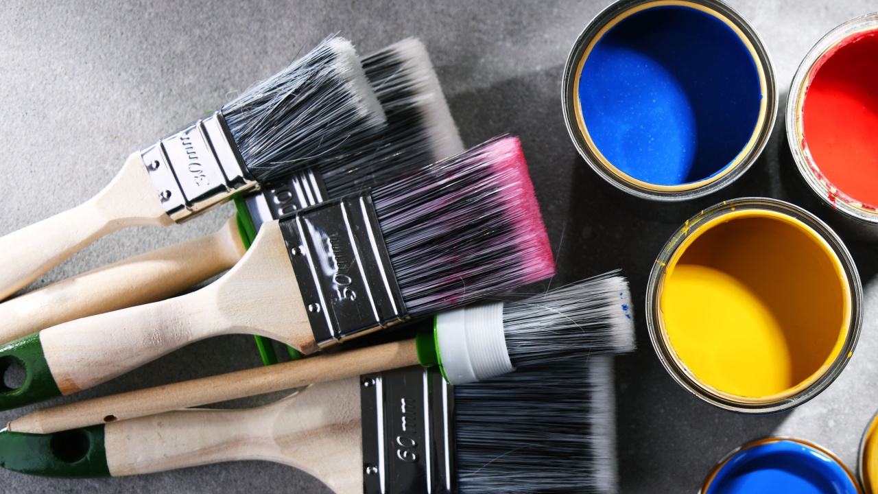 Paint cans and paintbrushes of different size for home decorating purposes.