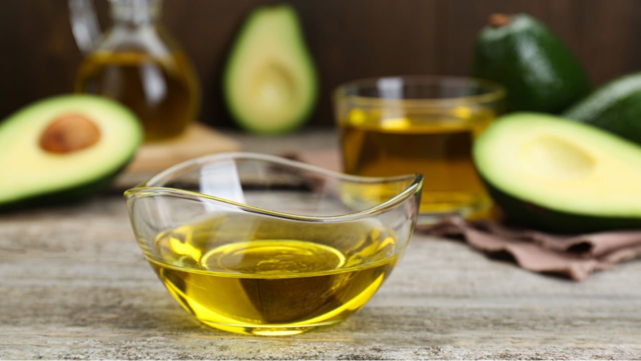 Bowl with avocado oil on wooden table