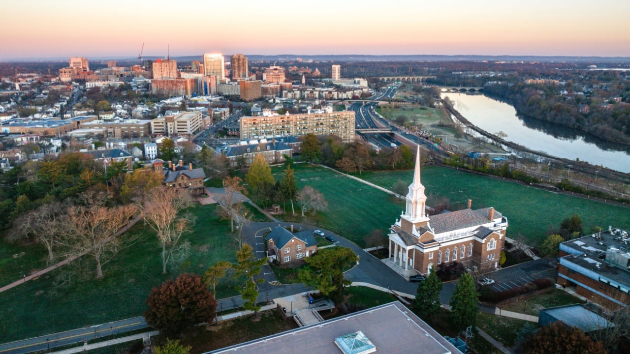 A drone view of a city skyline with buildings near the river at sunrise in New Brunswick, Rutgers, Hub City, USA