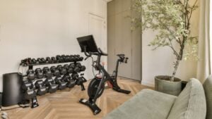 a living room with an exercise bike in front of the tv and other equipment on the wall is painted white