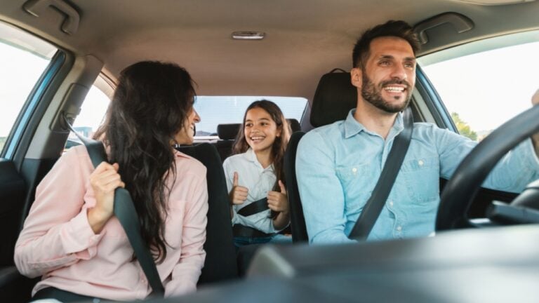 Auto purchase and rent. Happy caucasian family driving new automobile having test drive in city, enjoying road trip, panorama. Parents and child girl spending vacation traveling by car.