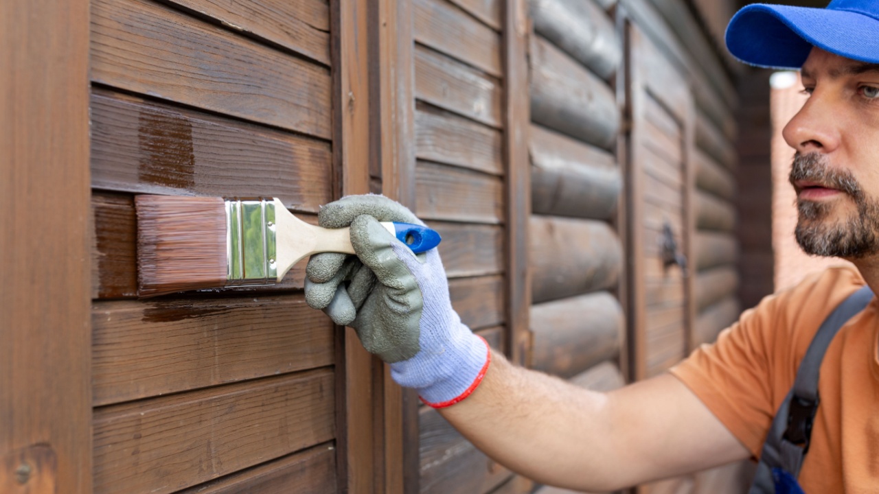 Protecting wooden house exterior with applying stain or paint.