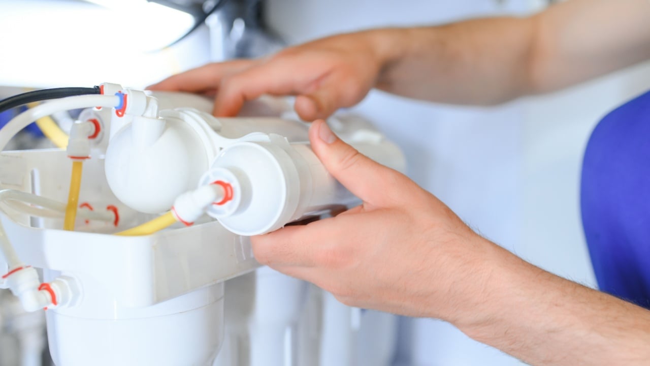 Plumber installs or change water filter. Replacement aqua filter. Repairman installing water filter cartridges in a kitchen. Installation of reverse osmosis water purification system