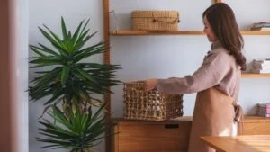 Portrait image of a woman holding a wooden basket while cleaning house