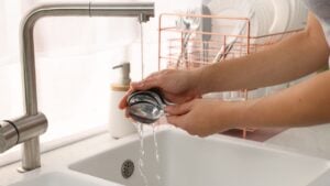 Woman washing spoons at sink in kitchen, closeup