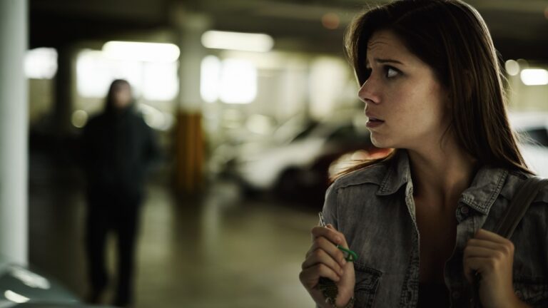 Female person, suspicious and parking lot with anxiety, worried and stressed for safety and concern. Woman, in danger and scared with backpack, terror and afraid for scary place and living in fear