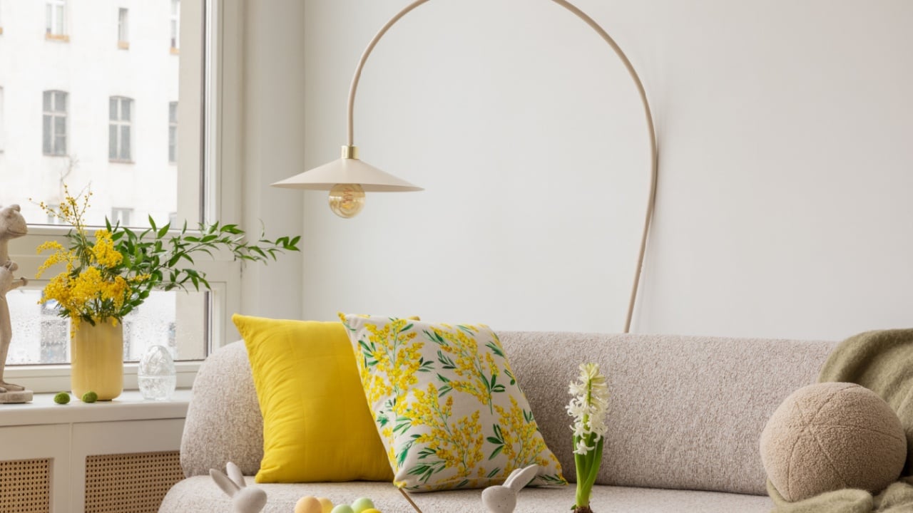 Interior design of spring living room with design sofa, furniture, vase with tulips, easter decorations, pillows