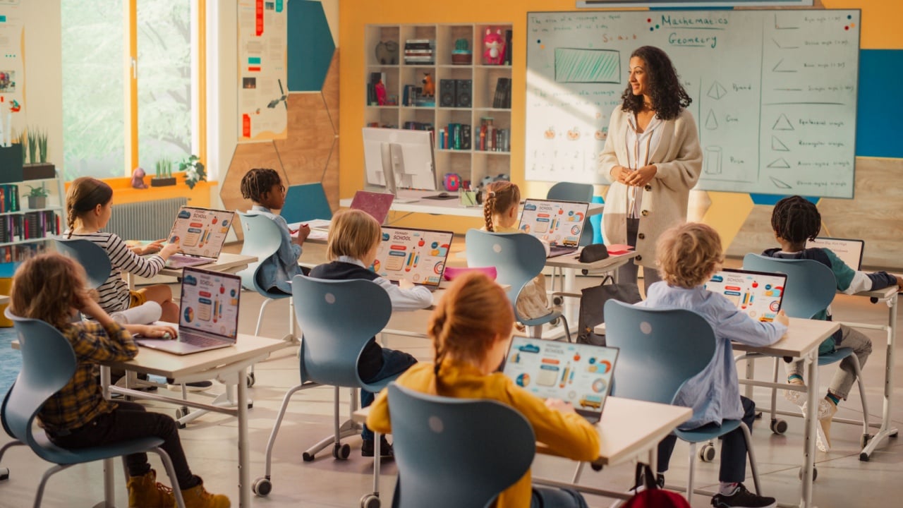 Elementary School Children Learning Basic Computer Knowledge: Teacher Educating Smart Diverse Kids in a Modern Colorful Classroom. Schoolchildren Getting Experience with Technology