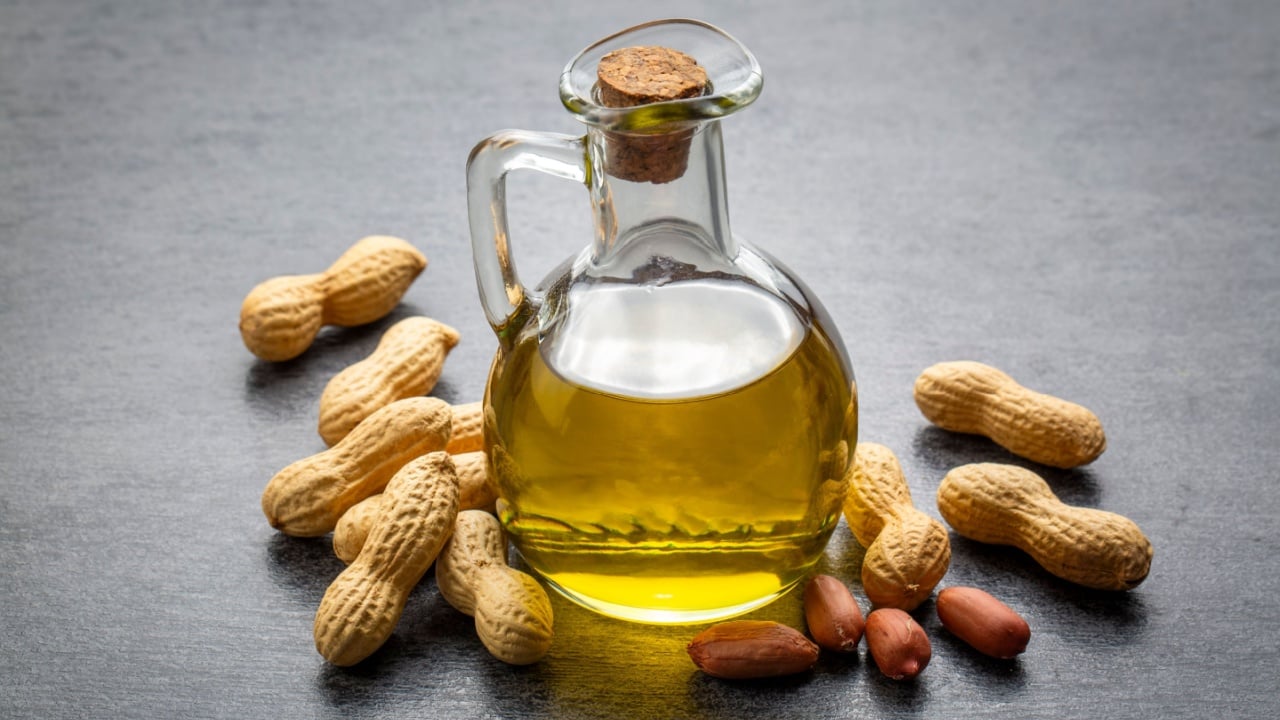 Peanut oil in glass bottle and peanuts 
