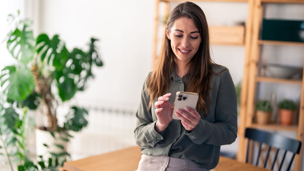 Successful confident woman entrepreneur with mobile phone indoors.