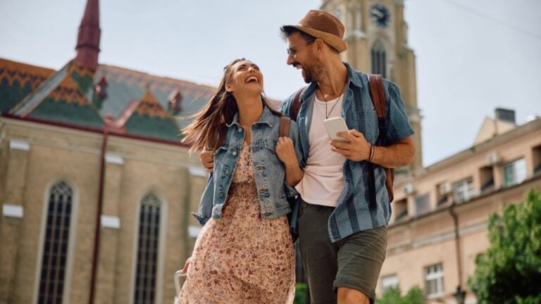 Happy couple of tourists laughing and having fun while walking in the city.