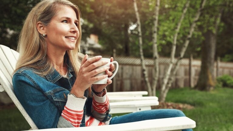 Coffee, outdoor and woman relaxing in backyard for calm, peace and break on weekend at home.