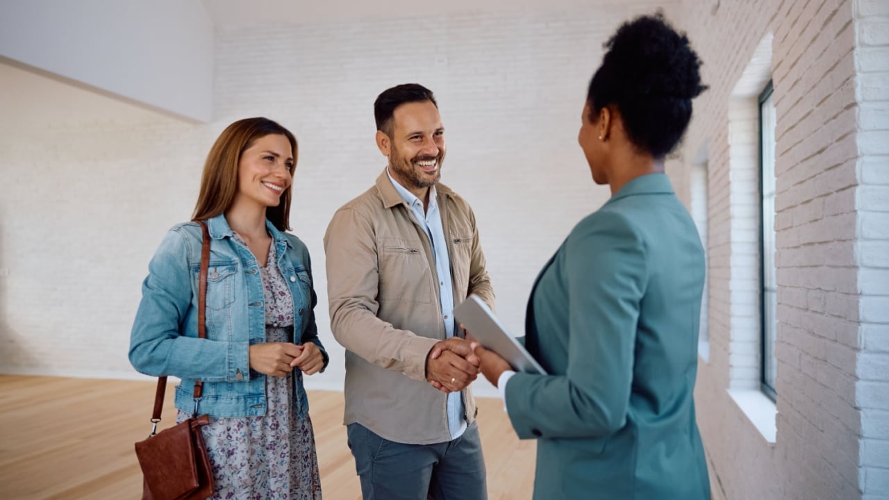 Happy couple greeting real estate agent while buying new house.